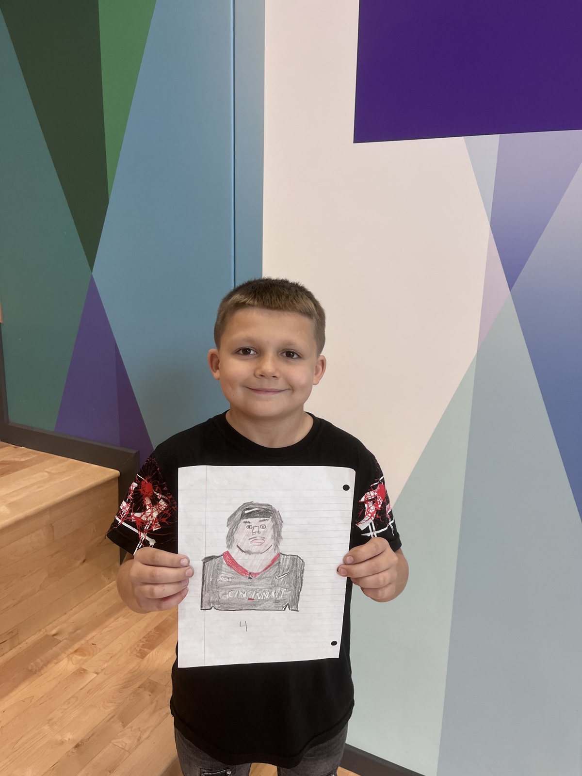 Student holds artwork he drew of UC Football player.